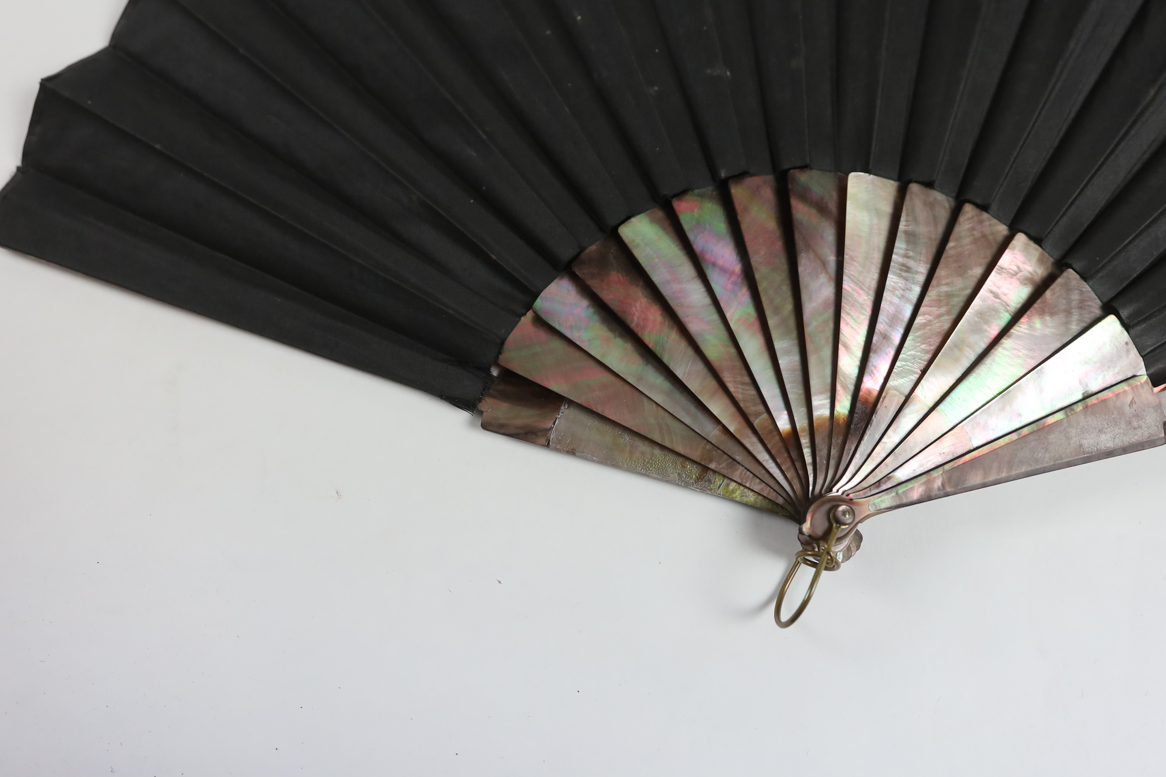 A late Victorian Chantilly black lace and tortoiseshell fan with a central painted cartouche and a mother of pearl and hand painted fairy and cherub fan, indistinctly signed